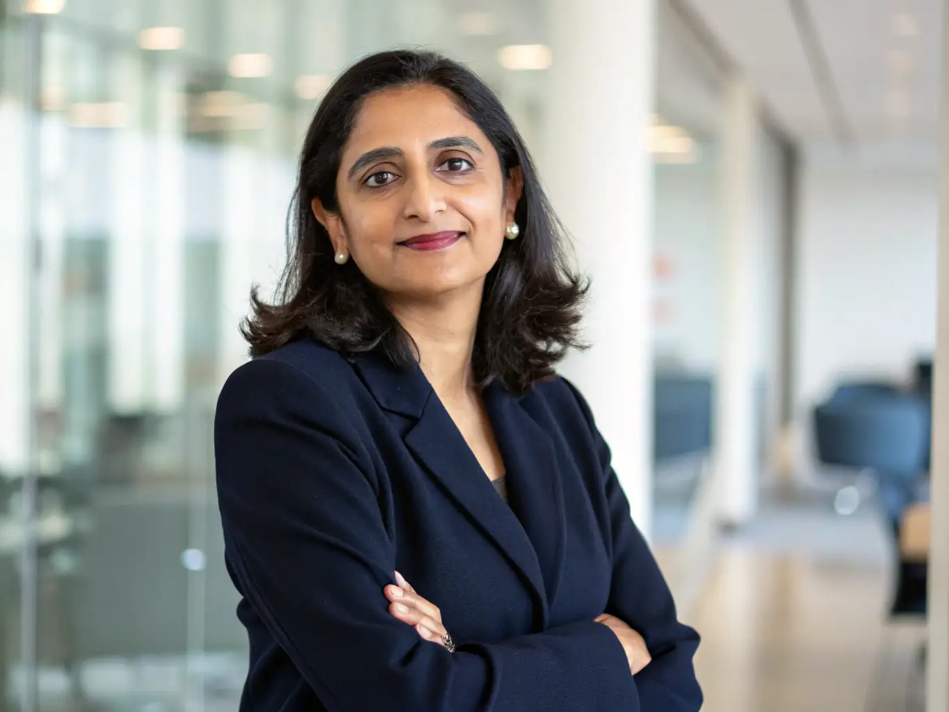 A professional headshot of Dr. Anya Sharma, a leading AI researcher, smiling confidently. She is wearing a business suit and standing in front of a blurred background of a tech conference.